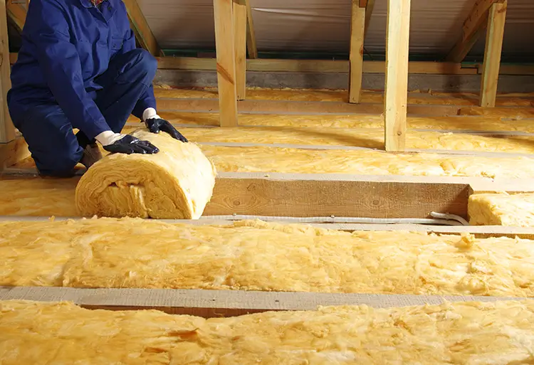 Worker unrolling wool into the floor for insulation