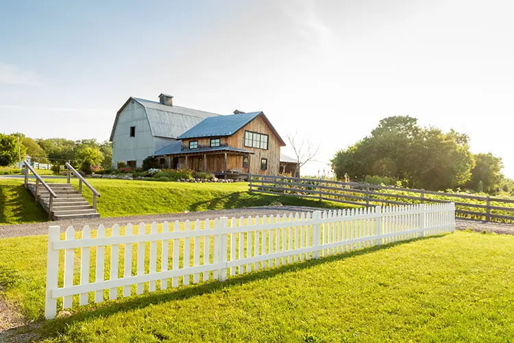 White picket fence surrounding a farmhouse